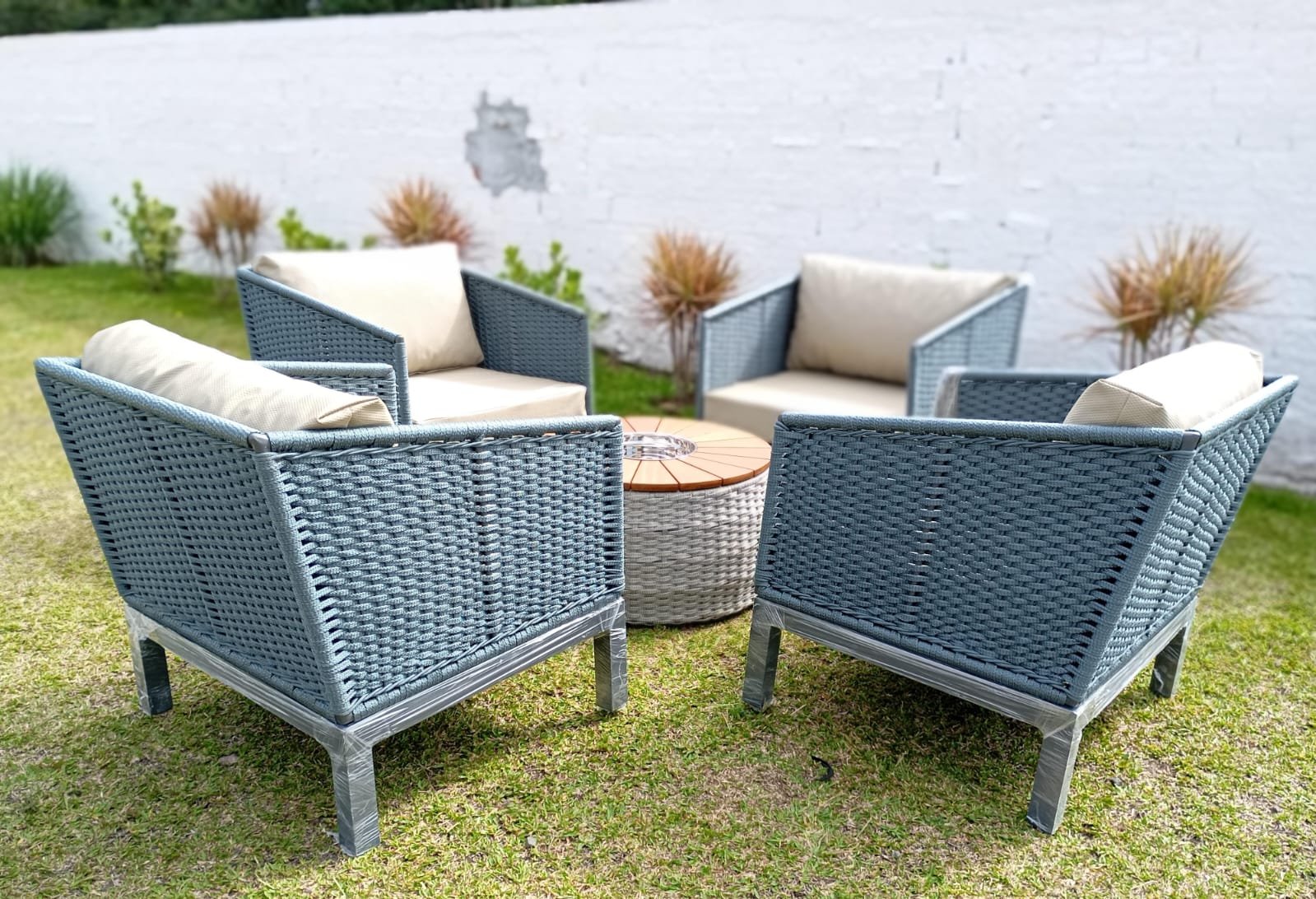 Quatro poltronas cinza ao redor de mesa com firepit