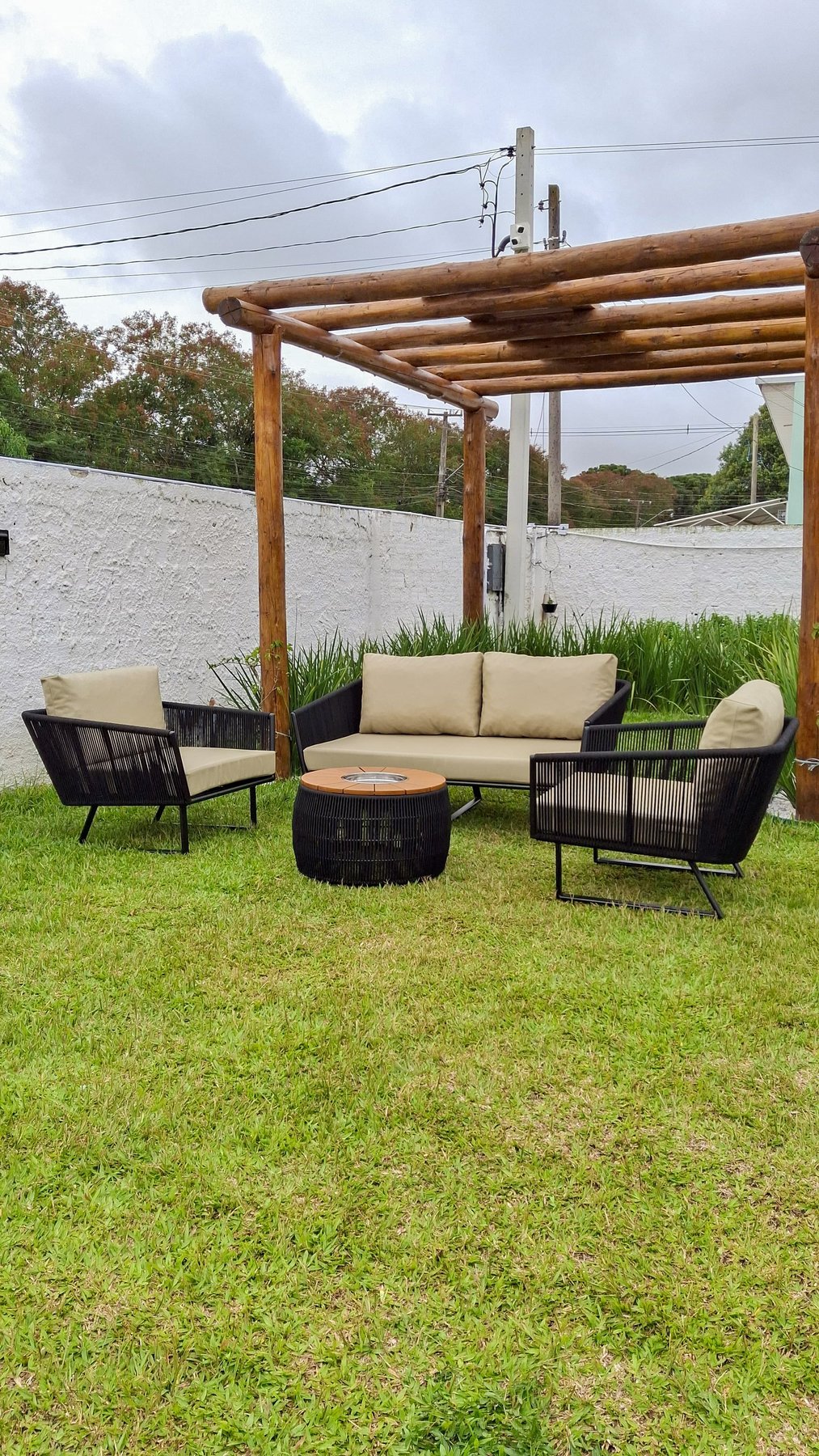 Conjunto lounge preto com almofadas bege sob pergolado