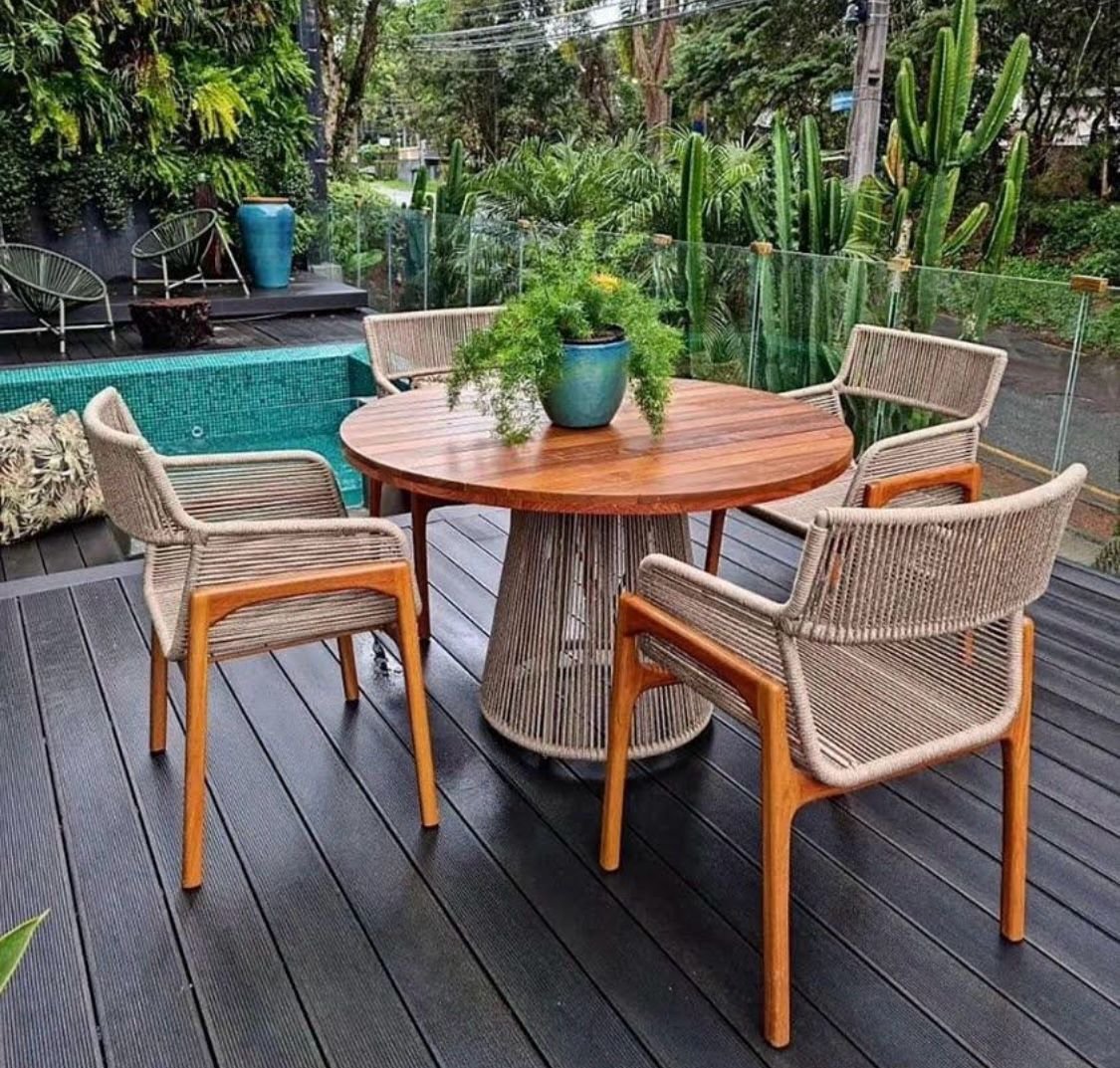 Mesa de madeira com base em corda e cadeiras bege no deck